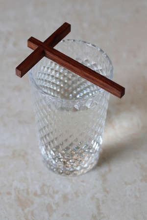 Glass of water, and christian cross during Lent. A solemn religious observance that begins on Ash Wednesday.の写真素材