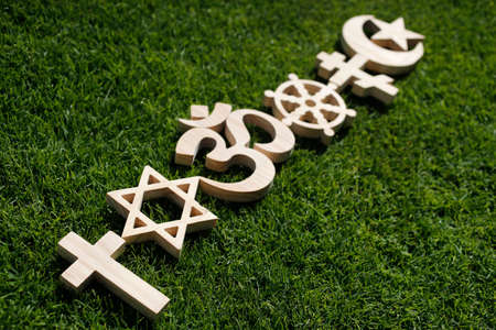 Religious symbols on grass. Christianity, Islam, Judaism, Orthodoxy Buddhism and Hinduism. Interreligious or interfaith concept.の写真素材