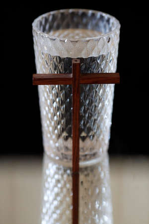Glass of water, and christian cross during Lent. A solemn religious observance that begins on Ash Wednesday.の写真素材