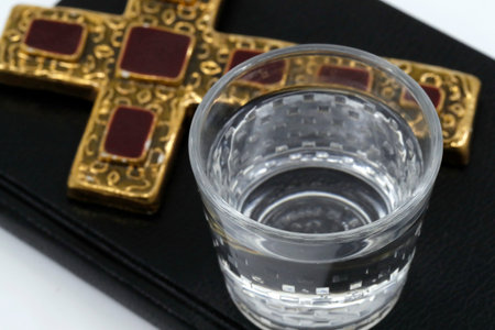 Christian cross, glass of water, and Bible during Lent. A solemn religious observance that begins on...