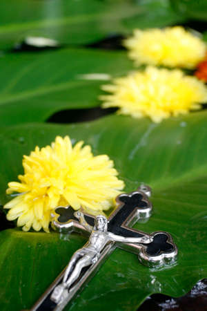Crucifix on a green leaf and yellow flowers.の写真素材