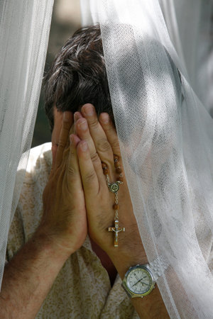 Man praying with rosary. France.