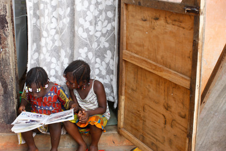 Two sisters reading a book. Daily life in Africa. Togo.のeditorial素材