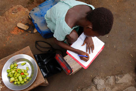 African girl doing homework outdoors. Togo.のeditorial素材