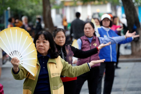 Early morning tai chi session along the banks of Hoan Kiem lake. Exercises with fans. Ha Noi. Vietnam.のeditorial素材
