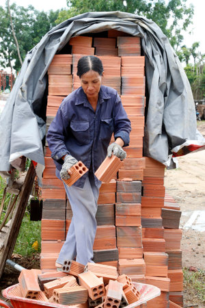 Woman working on construction site. Red bricks Vung Tau. Vietnam.