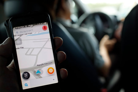 A man holds up a smartphone showing the Grab app. Ho Chi Minh city. Vietnam.のeditorial素材