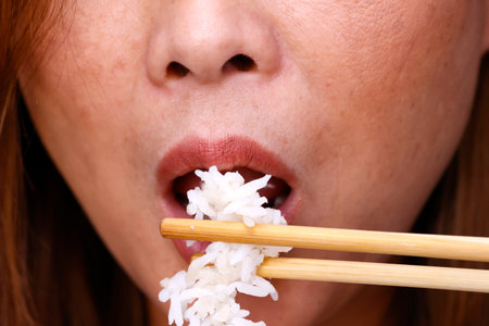Woman eating steamed rice. Closeup on chopsticks.の写真素材