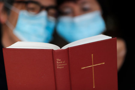 Man and woman reading the bible with a disposable mask to avoid contagious coronavirus (COVID-19). France.のeditorial素材