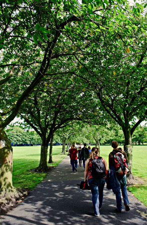 Students walking across the Meadows in Edinburgh, Scotland,on a sunny day in the shade of an avenue of treesの写真素材
