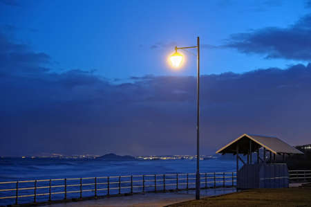View over the Firth of Forth from Fife, Scotland, towards Inchkeith and Edinburgh at nightfall on a stormy evening. A weatherfront is passing. Waves are blurred by long exposure.の写真素材