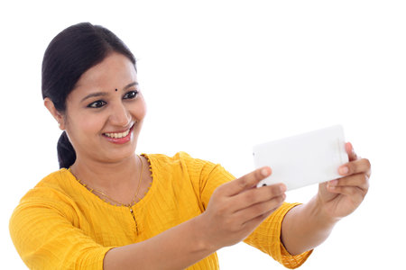 Happy young woman taking a selfie against white backgroundの写真素材