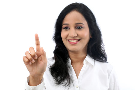 Young businesswoman touching virtual screen against whiteの写真素材