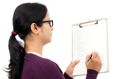 Young female student holding clipboard and writing notes