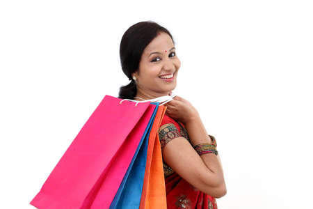 Traditional Indian woman holding shopping bags against whiteの写真素材