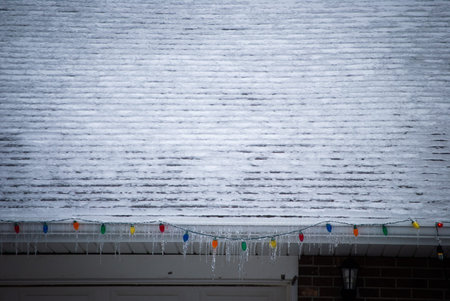 Icey Christmas lights hanging from snowy roof
