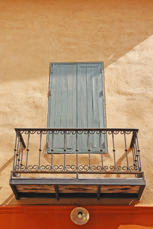Old wooden window close and iron balcony on orange wallの写真素材