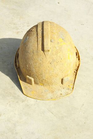 Dirty yellow hard hat on Concrete floor.の写真素材