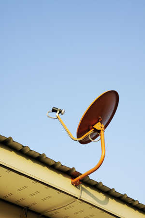 Satellite dish mounted on the roof with blue sky の写真素材
