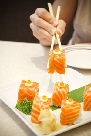 woman hand holding salmon sushi with chopsticksの写真素材