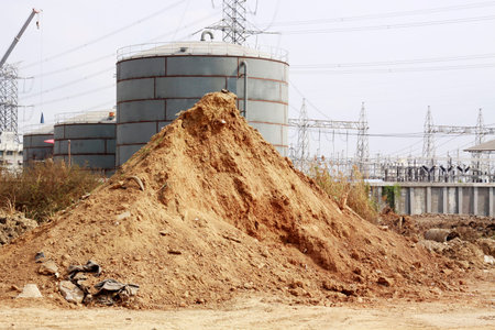 Pile of dry soil and sand in front of big Industrial tanks のeditorial素材