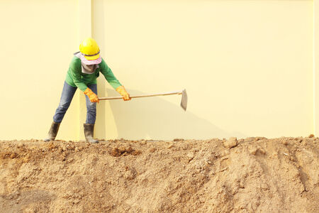 Laborer digging with hoe on construction siteの写真素材