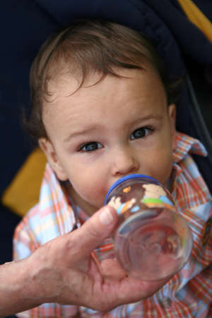 Cute little boy drinking from the bottleの写真素材