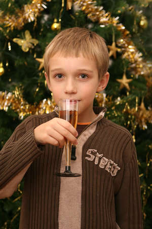 Little boy drinking champagne in front of a Christmas treeの写真素材