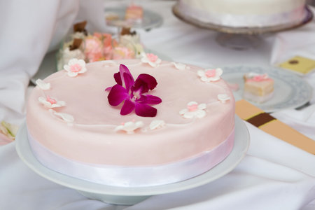 Wedding cake with pink icing decorated with an orchid flowerの写真素材