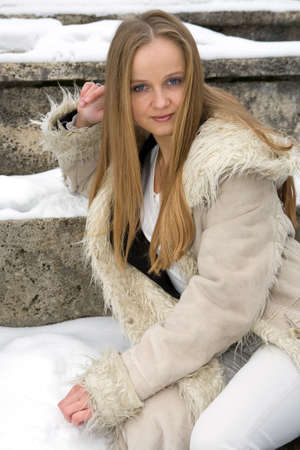 Blond freckled girl in fur coat on the snowの写真素材