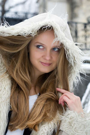 Blond girl in fur coat playing with the hoodの写真素材