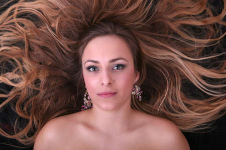 Beautiful blond girl lying on her back on black backgroundの写真素材