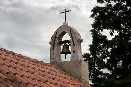 Old belfry with cross against gray stormy skyの写真素材