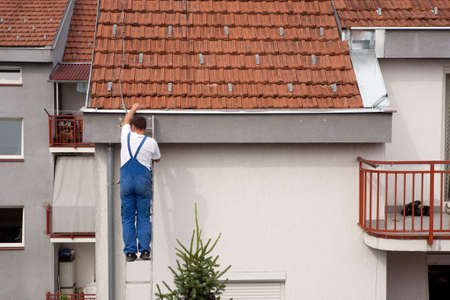 Man on a ladder climbing on the roofの写真素材