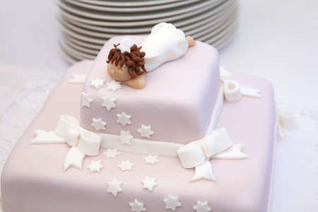 Pink christening cake with little angel on topの写真素材