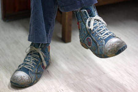 Man with crossed legs in blue shoesの写真素材