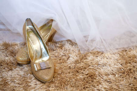 Golden wedding shoes on a carpet with copy space on the rightの写真素材