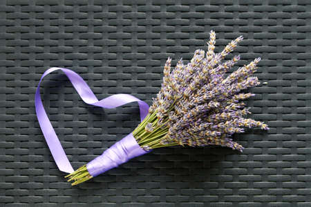 Lavender bouquet on a textured background with heart-shaped ribbonの写真素材