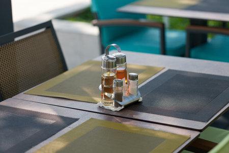Jars with seasoning - vinegar, oil, salt, pepper are standing on restaurant table outdoors