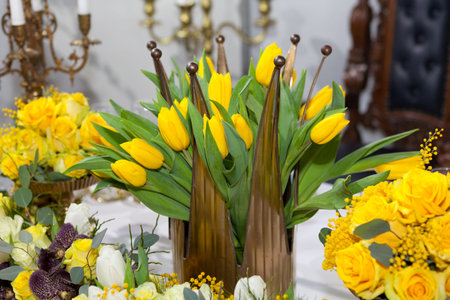 Crown shaped vase with yellow tulips, table set for an event party or wedding reception, luxury elegant table settingの写真素材