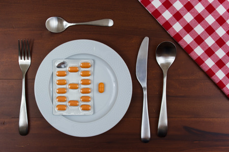white dish with cutlery and pills on wooden tableの写真素材