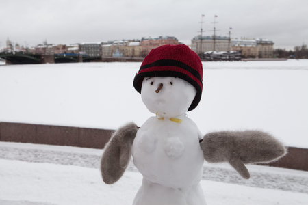 A snowman in warm clothing standing against the backdrop of St. Petersburg, Russia.の写真素材