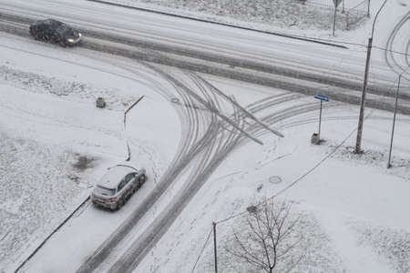 Snowy winter in the city, cloudy day, two cars at the intersectionの写真素材