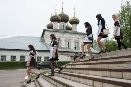 Ustyuzhna Vologda region, Russia - May 22, 2015: schoolgirl in uniform climb the stairs on the background of white stone five-domed Orthodox churchのeditorial素材