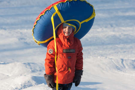 St. Petersburg, Russia - February 11, 2015: People ride with inflatable sled in the winter clear day in the suburbs of a big city at the weekend, boy with inflatable sled colorのeditorial素材