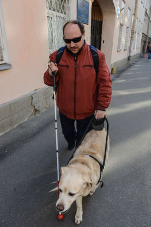 St. Petersburg, Russia - May 29, 2012: A blind man of 50 years during training walking around the city with the help of a guide dog breed Labrador on the main street.のeditorial素材