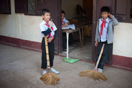 Vientiane, Laos - December 11, 2013: Students in school uniforms on a break between classes in the school yard playing various children's games. Fun, laughter, smiles.のeditorial素材