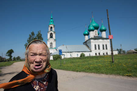 Levashovo village, Yaroslavl Region, Russia - May 27, 2015: The oldest woman - a parishioner of the church after the service returns home. The Church of the Resurrection in the countryside is an architectural monument of the 18th century. Summer, sunny daのeditorial素材
