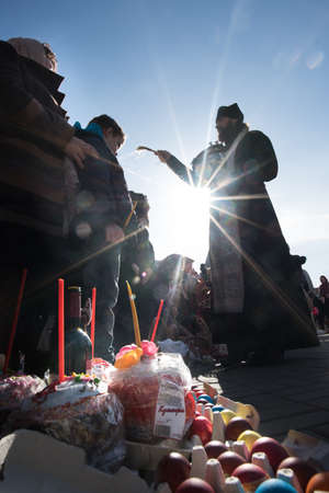 St. Petersburg, Russia, April 11, 2015: Traditional orthodox paschal ritual - priest blessing easter eggs and kulitches with holy waterのeditorial素材