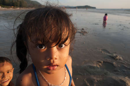 Lanta Krabi, Thailand - February 2, 2014: A girl plays on the beach while their parents collect marine molluscs at low tideのeditorial素材